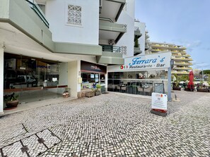 A Ferrara Restaurant Bar with a tiled pavement, potted plants, and a view of a multi-story building in the background. - Vilamoura Central Beach 1 by Homing (Loulé)