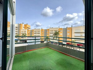 A balcony with artificial grass, a metal railing, and a view of multi-story buildings. - Vilamoura Central Beach 1 by Homing (Loulé)