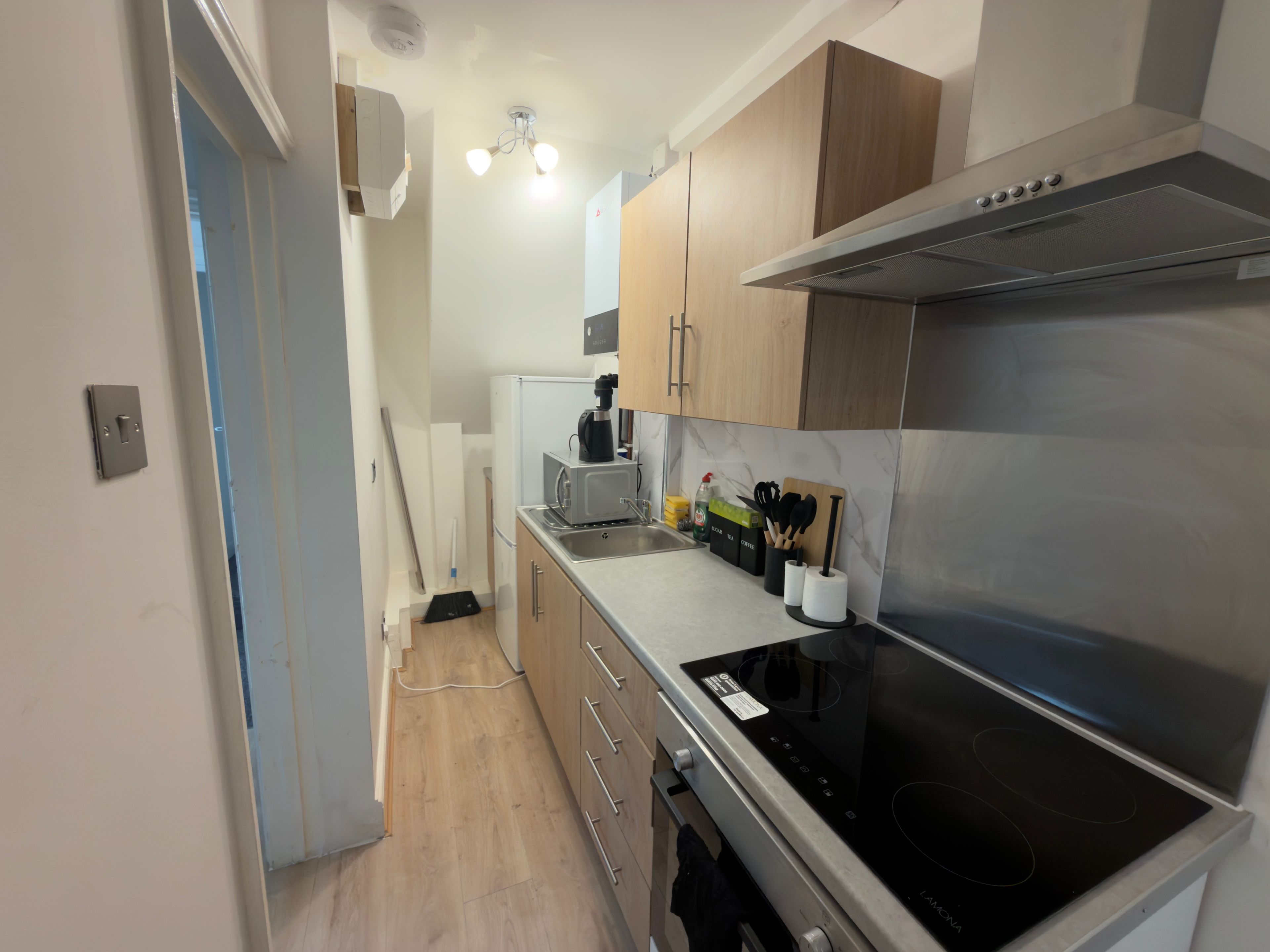 A modern kitchen with a built-in stove, a coffee maker, and various utensils on the counter.