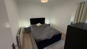 Un dormitorio con cama, mesitas de noche, un calentador y una lámpara en el techo.