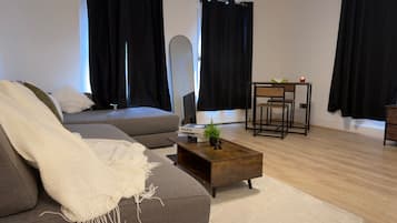 Un salon moderne avec un canapé gris, une table basse en bois et un fauteuil à monture noire.