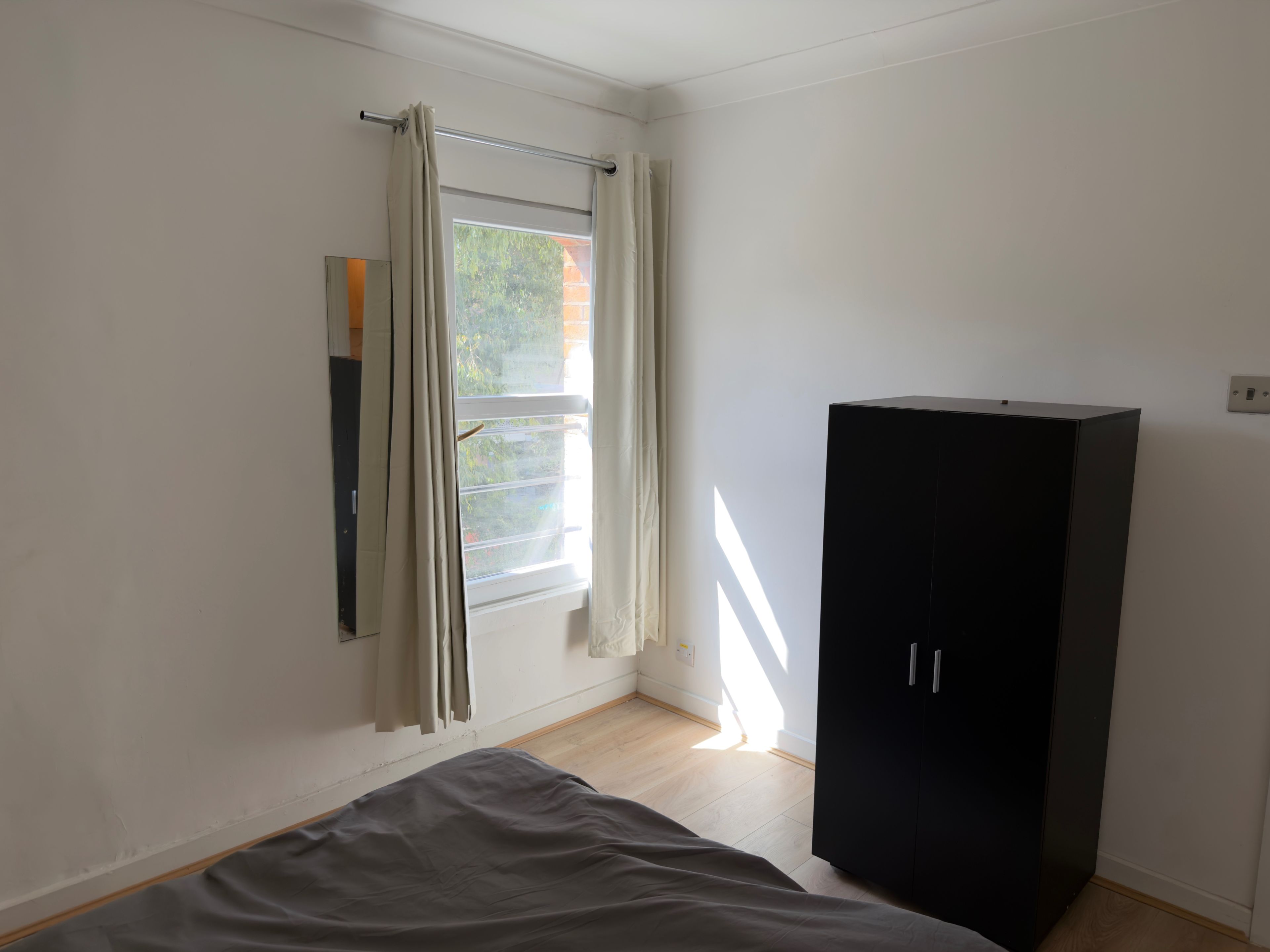 Una camera da letto con un letto, un armadio e una finestra con tende.