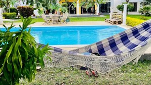 Un área de piscina con una hamaca, sillas y una terraza.