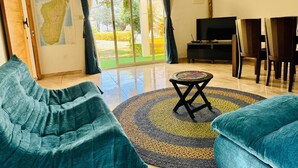 Una sala de estar con un sofá, una televisión y un comedor con sillas.