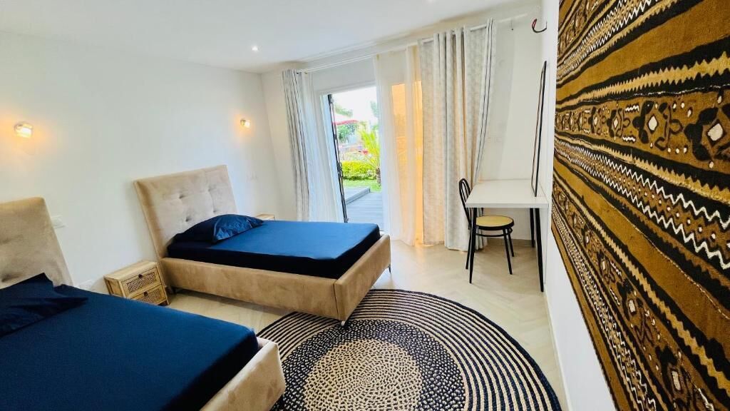 Habitación de hotel con dos camas, un escritorio y vistas al exterior.