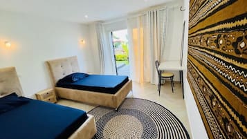 Habitación de hotel con dos camas, un escritorio y vistas al exterior.