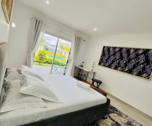 Habitación de hotel con cama, escritorio y vista a una piscina.