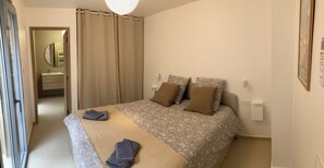 Ein Schlafzimmer mit einem Bett, Vorhängen, einem Nachttisch und einer Wandleuchte.