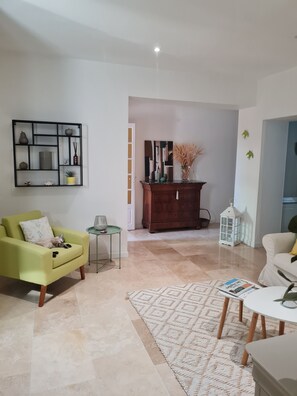 A living room with a green armchair, a white sofa, a coffee table, and a patterned rug. - Chic et Nature (Avignon)