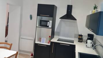Uma cozinha moderna com armários pretos, micro-ondas, máquina de café e pia.