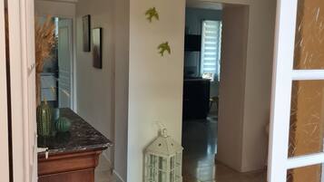 A hallway with a wooden cabinet, a white lantern, and a door leading to another room.