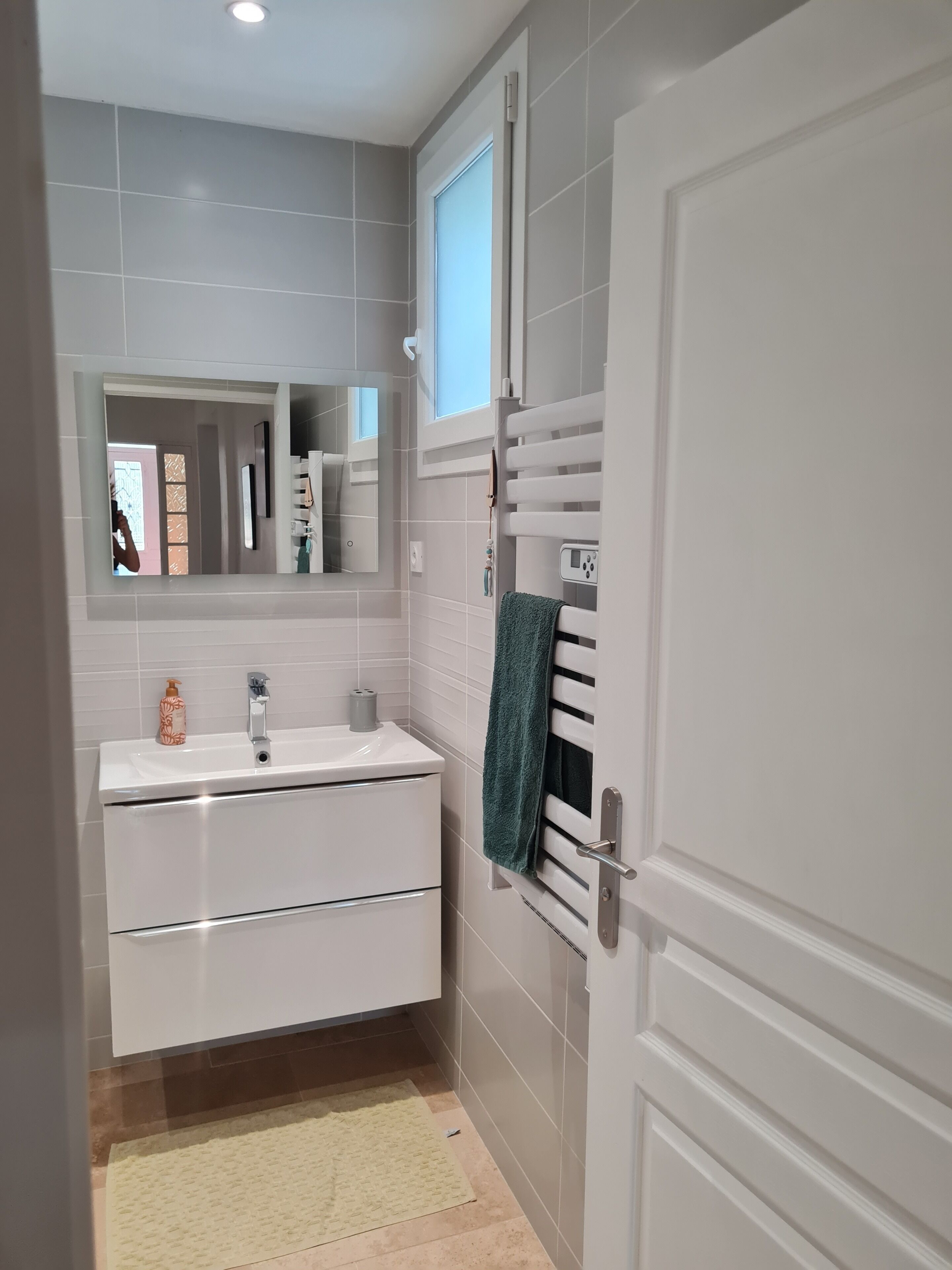 Ein Badezimmer mit weißem Waschbecken, Spiegel und Handtuchhalter.