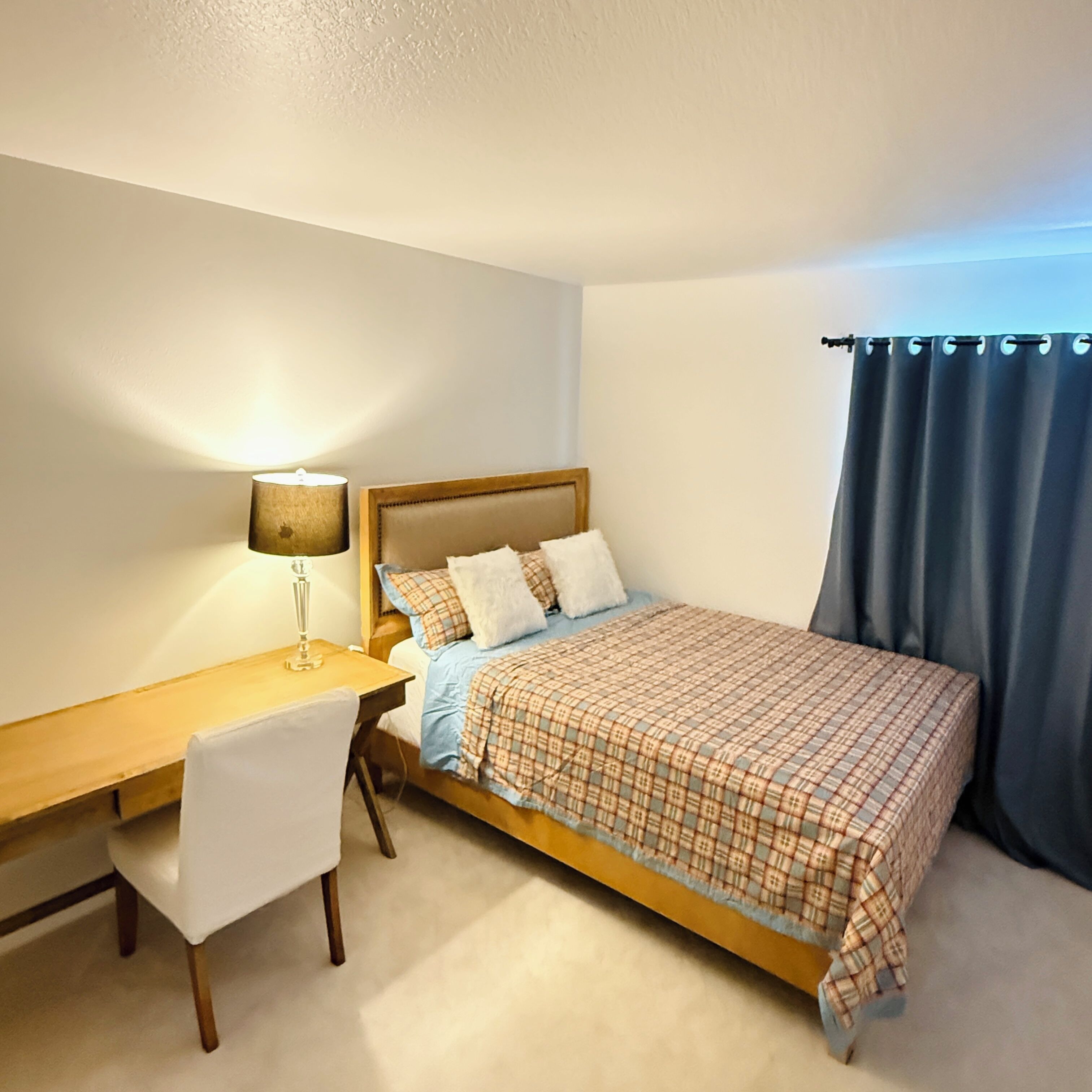 A bedroom with a bed, a desk, and a chair.