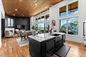 Un'ampia cucina con un'isola grande, pavimento in legno e ampie finestre con vista sull'esterno.