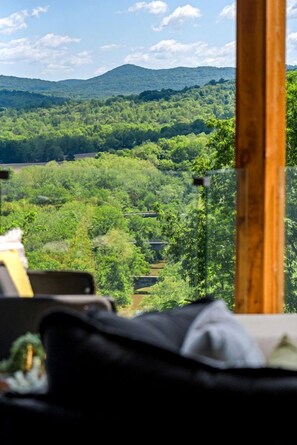 Ein Zimmer mit Blick auf eine bewaldete Landschaft und einen Berg in der Ferne.