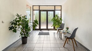 Ein Flur mit Zimmerpflanze, Stuhl, kleinem Tisch und Glastür zum Balkon.