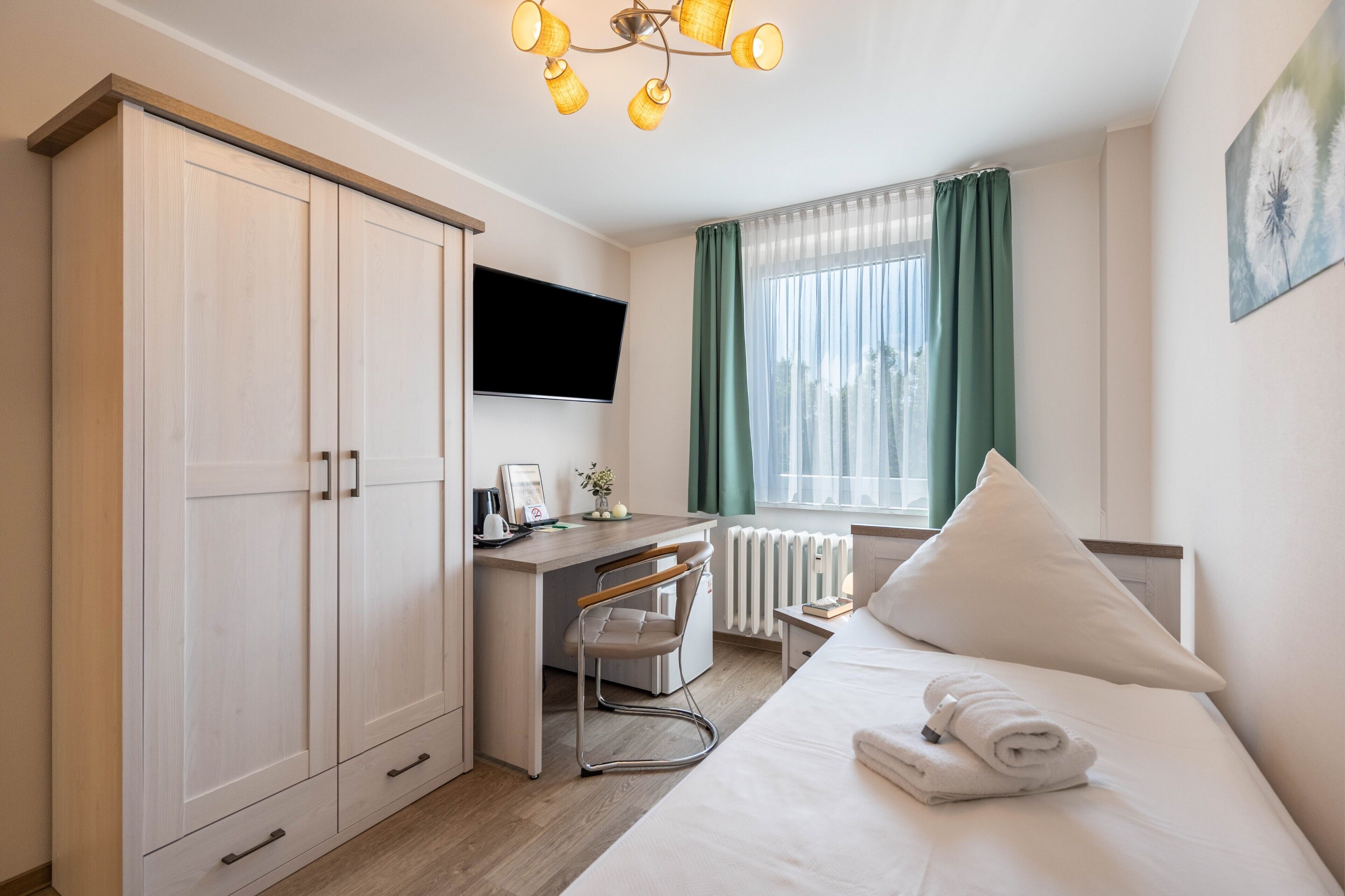 Une chambre d’hôtel équipée d’un lit, d’un bureau, d’une télévision et d’une armoire.