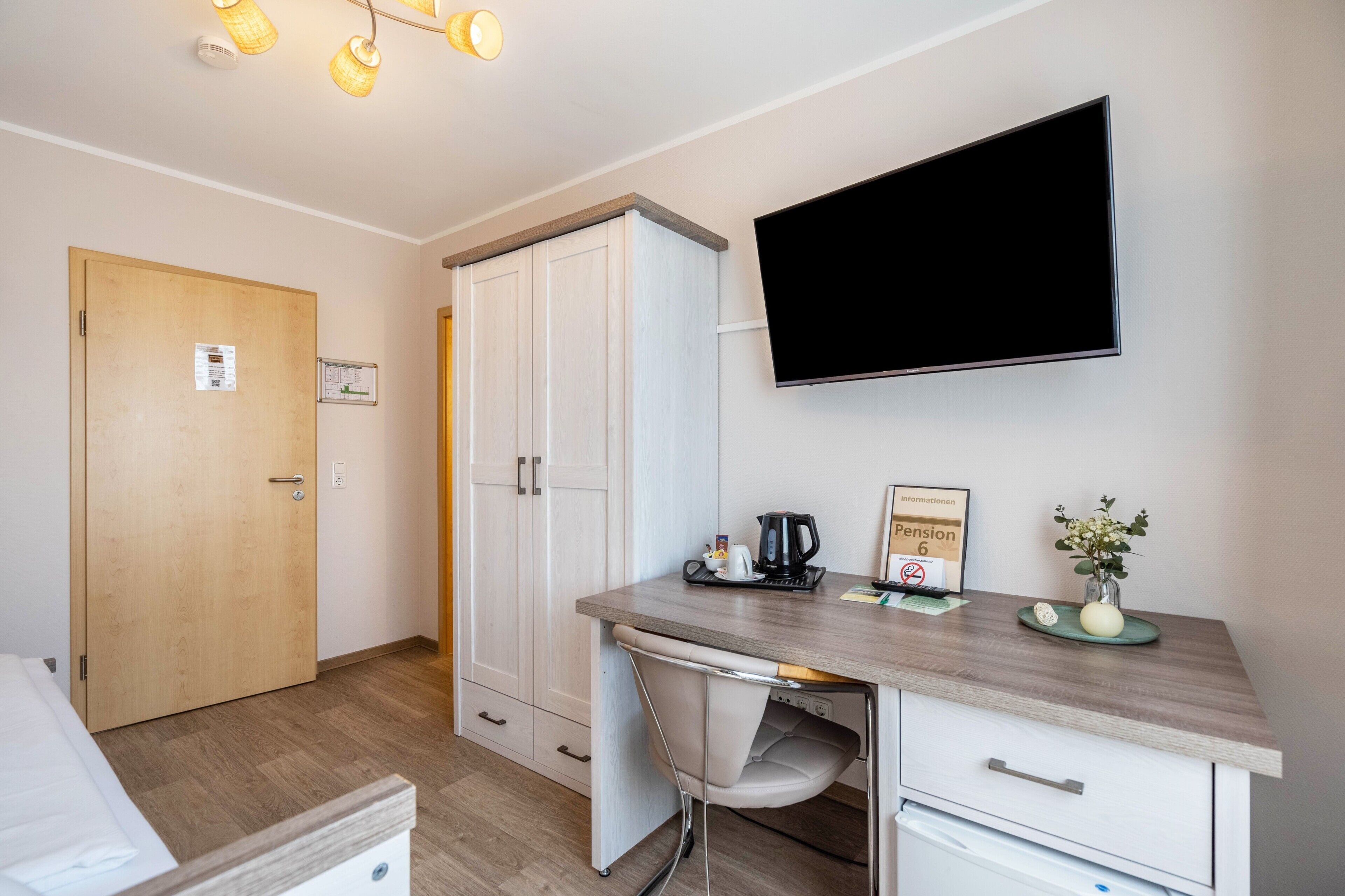 Une chambre d’hôtel avec un bureau en bois, un téléviseur à écran plat, une armoire et un lit.