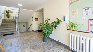 Ein Flur mit Treppe, Heizkörper und einem Schwarzebrett mit Aushängen.