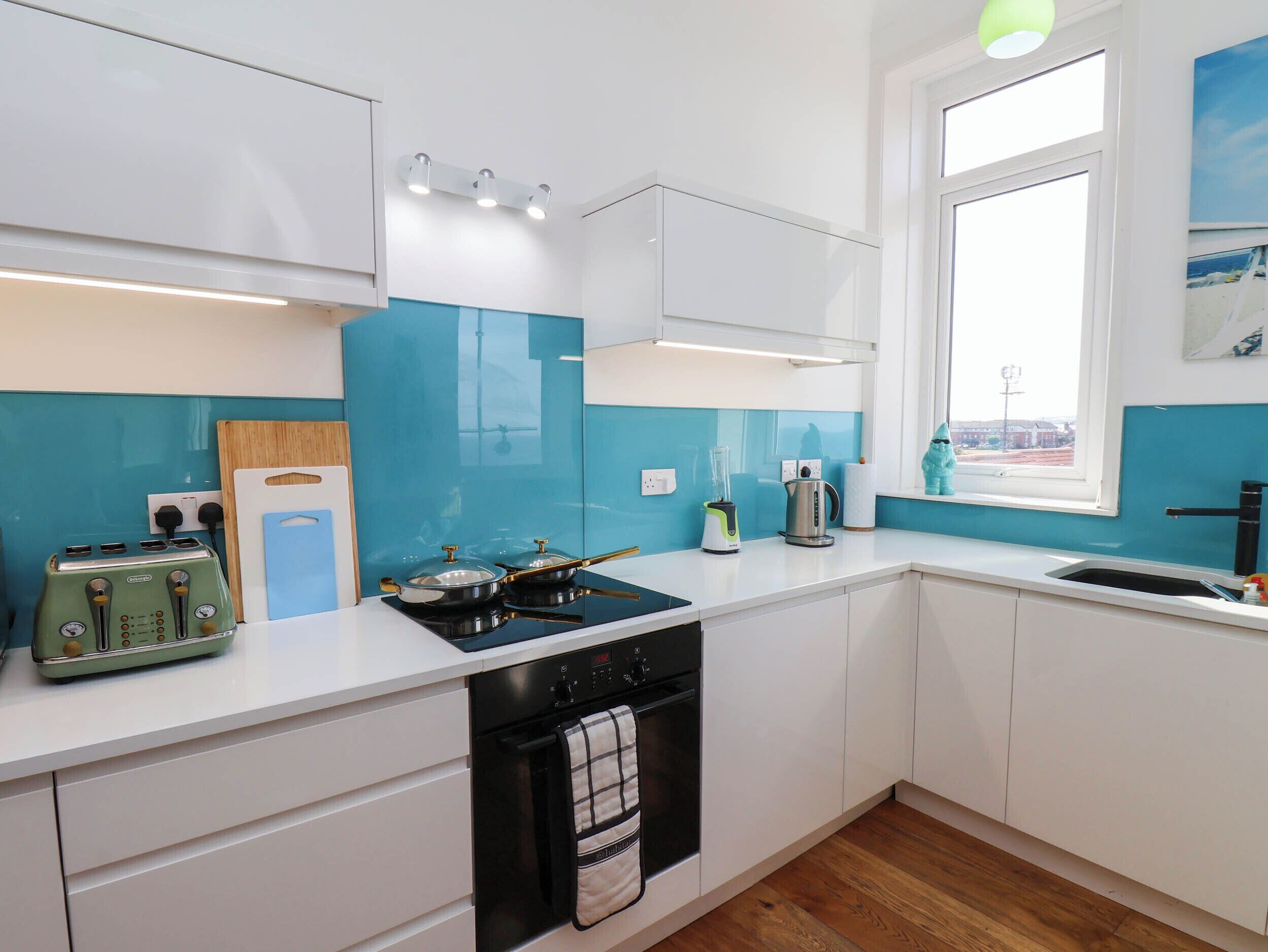 A modern kitchen with white cabinets, a black stove, and a window with a view.