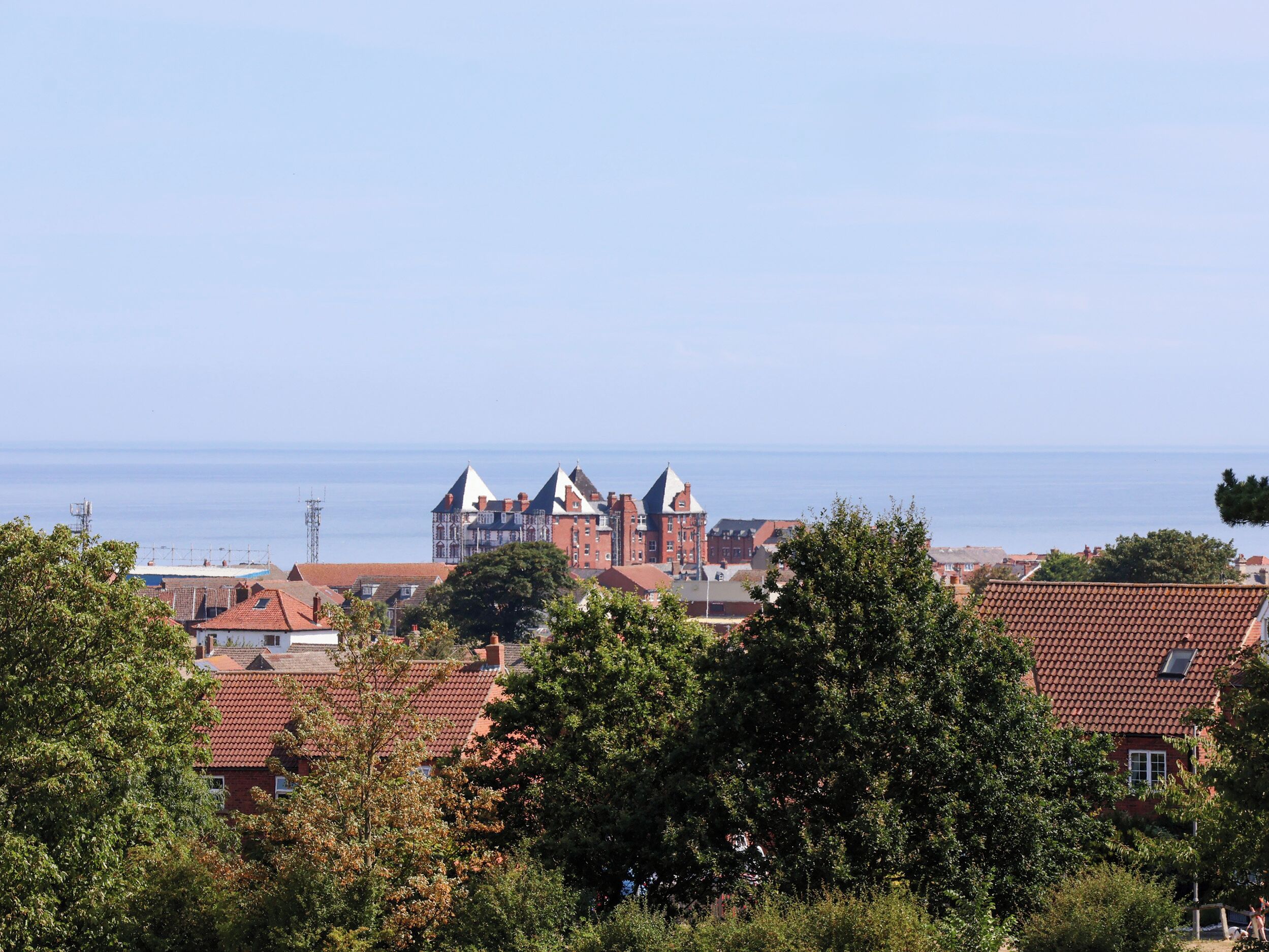 A coastal town with red-roofed buildings and a large castle-like structure.