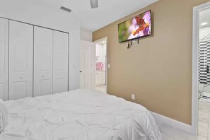 Une chambre à coucher avec un lit, un téléviseur fixé au mur et une armoire.