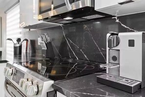 A kitchen with a black marble countertop, stainless steel appliances, and a coffee machine. - Luxury Home/Heated Pool/TPA Airport/Disney (Tampa)