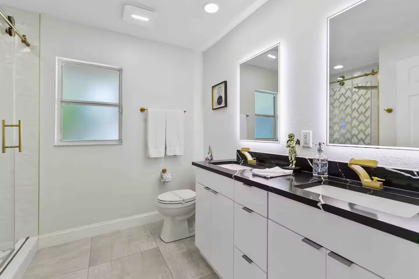 A modern bathroom with a toilet, bidet, and a large mirror above the sink.