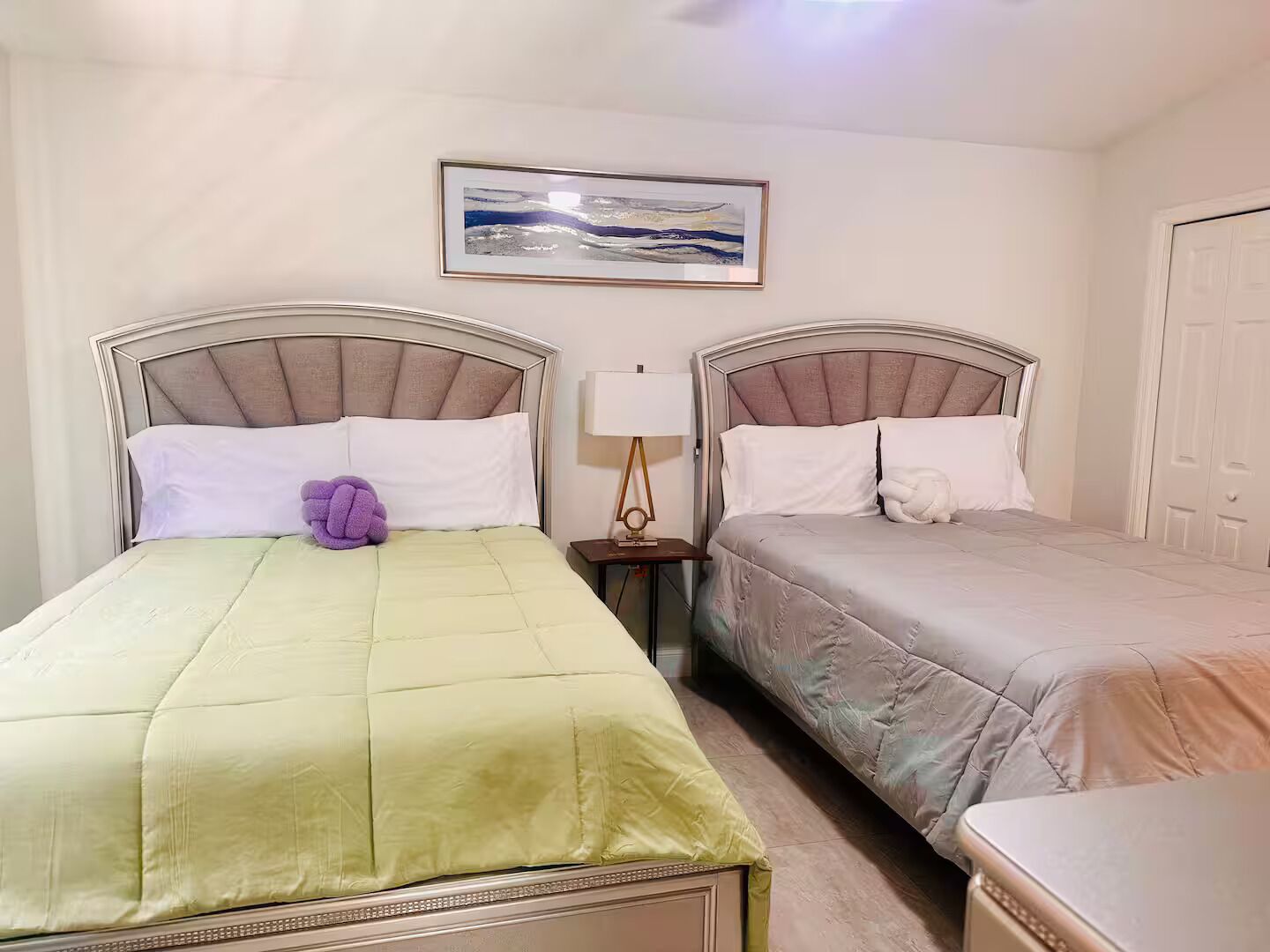 Habitación de hotel con dos camas, una mesita de noche con lámpara y un cuadro en la pared.