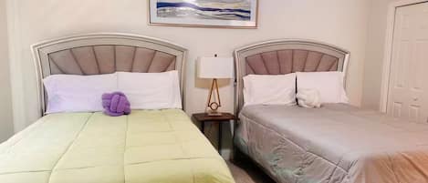 Habitación de hotel con dos camas, una mesita de noche con lámpara y un cuadro en la pared.