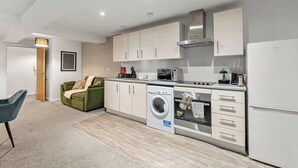 Une cuisine compacte équipée d’un lave-linge, d’un four à micro-ondes et d’un four encastré.