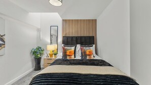 Une chambre à coucher avec un lit, une table de chevet, une lampe et une plante en pot.