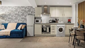 Un espace de vie compact comprenant un coin cuisine, un lave-linge, un coin repas et un canapé.