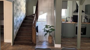 En trappa som leder upp till andra våningen, ett köksområde med moderna vitvaror och en krukväxt.