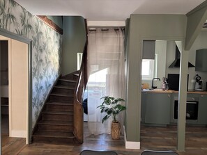 Eine Treppe zu einer zweiten Etage, ein Küchenbereich mit modernen Geräten und ein Blumentopf.