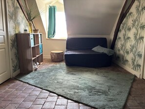 Ein gemütliches Zimmer mit einem dunkelgrauen Sofa, einem kleinen runden Tisch und einem grünen Teppich.