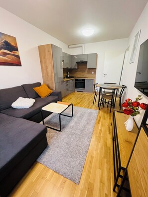 Ein gemütlicher, kompakter Wohnbereich mit Sofa, kleinem Tisch, Essbereich und Küchenzeile.