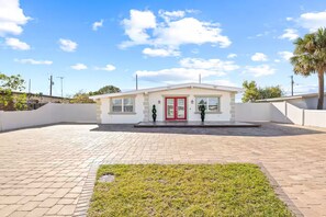 A modern building with a red door, a small front garden, and a paved driveway. - Gorgeous Home/Heated Pool/Clearwater/Tampa/Disney (Tampa)