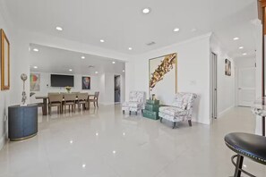 A spacious living area with a dining set, two armchairs, and a bar stool. - Gorgeous Home/Heated Pool/Clearwater/Tampa/Disney (Tampa)