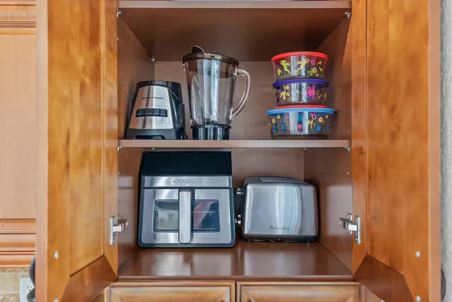 A kitchen with a coffee maker, blender, toaster, and stacked containers.
