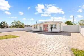 A building with a red door, a small porch, and a paved courtyard. - Gorgeous Home/Heated Pool/Clearwater/Tampa/Disney (Tampa)