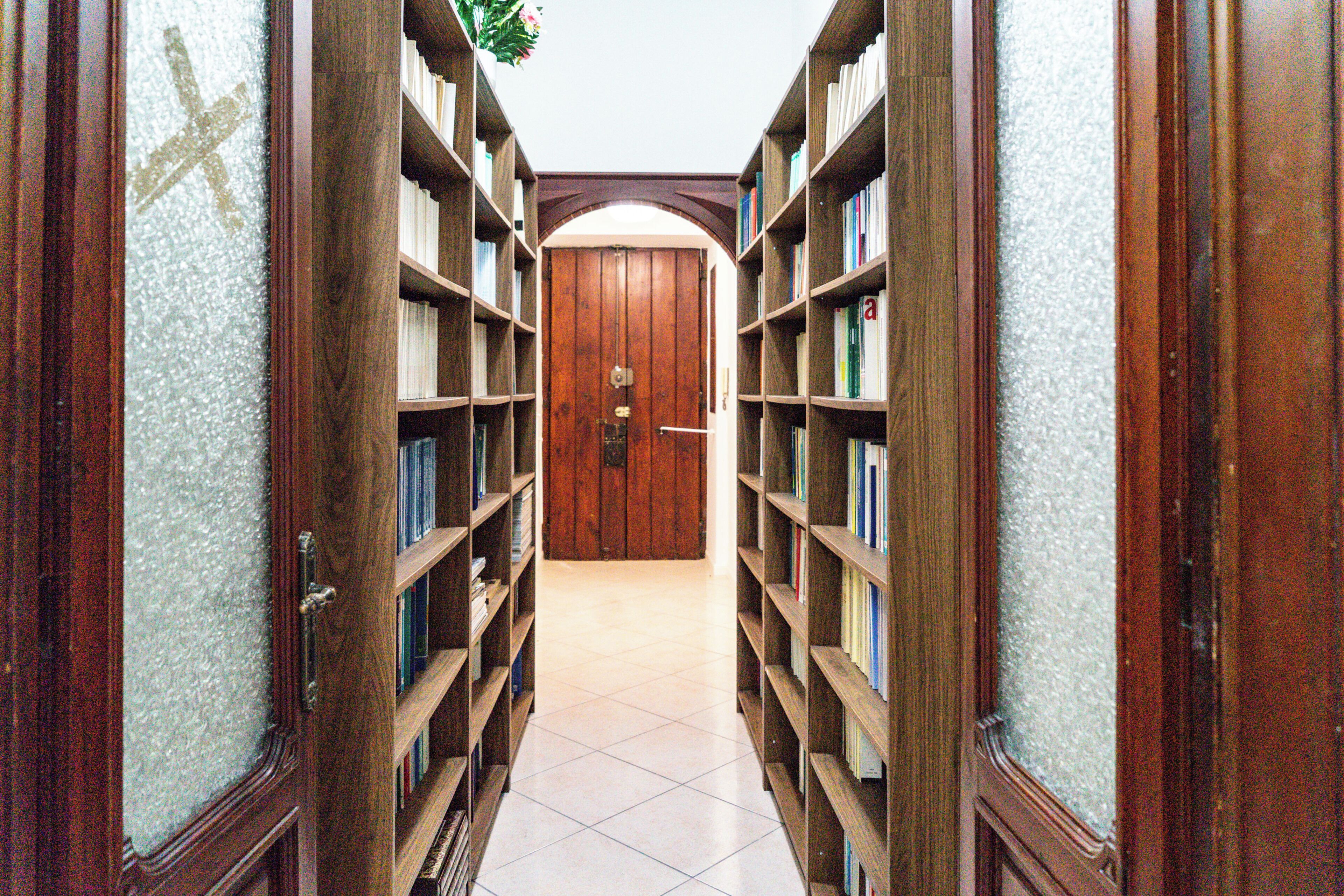 Ein Flur mit Bücherregalen an beiden Seiten, der zu einer Holztür führt.