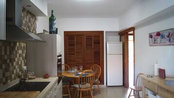 Een compacte keuken met een eethoek, met een houten tafel, stoelen en een koelkast.