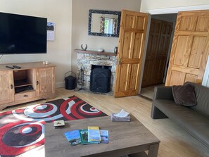 A living room with a television, wooden cabinet, fireplace, and a sofa. - 6 Riverfalls Clifden (Clifden)