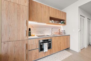 Een moderne keuken met houten kastjes, een marmeren aanrecht, een inbouwoven en een spoelbak.