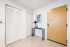 A hallway with a wooden door, a white wall, and a framed artwork. - The Crosby Balcony 1BR at Miami Worldcenter (Miami)