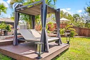 A covered outdoor seating area with a cushioned bench and a metal lantern. - Fancy Tampa Retreat/Disney/Heated Pool/Clearwater (Tampa)