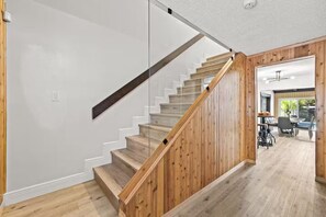 A staircase with wooden steps and a wooden handrail, leading to an open-plan living area with a dining table and chairs. - Fancy Tampa Retreat/Disney/Heated Pool/Clearwater (Tampa)