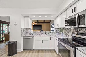 A modern kitchen with white cabinets, a stainless steel microwave, and a black stove. - Fancy Tampa Retreat/Disney/Heated Pool/Clearwater (Tampa)