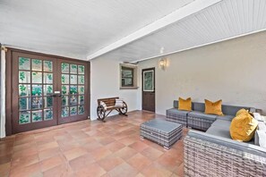 A room with a bench, a sofa, and a door with glass panels. - Fancy Tampa Retreat/Disney/Heated Pool/Clearwater (Tampa)